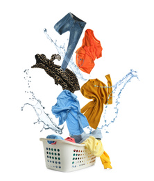 Different clothes with water splash falling into laundry basket against white background