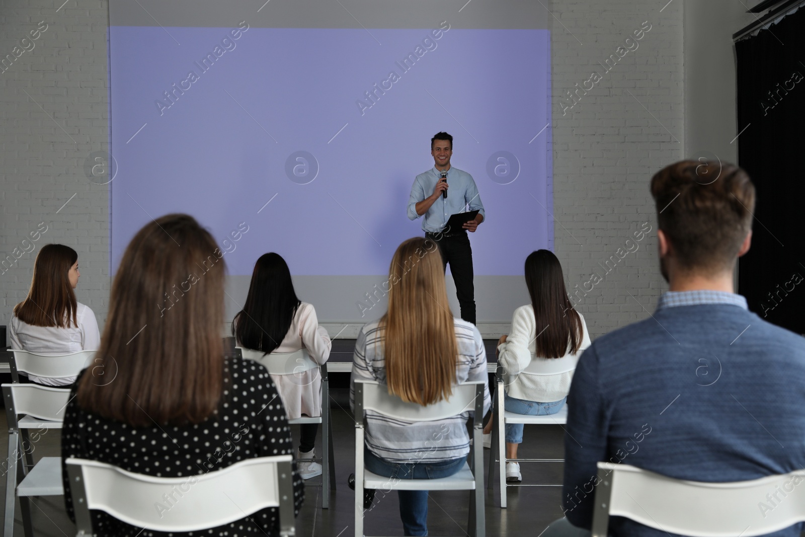 Photo of Male business trainer giving lecture in conference room with projection screen