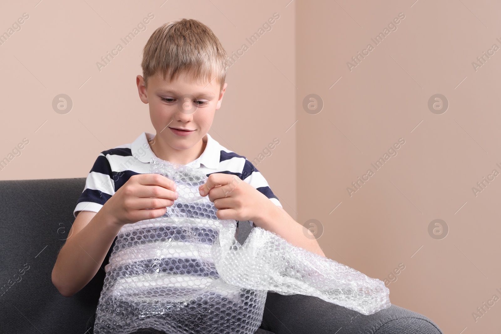Photo of Boy popping bubble wrap at home, space for text. . Stress relief