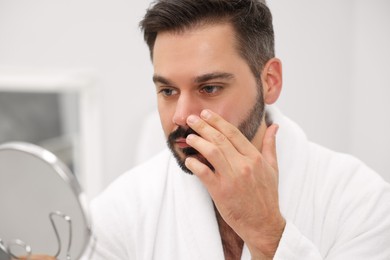 Photo of Man with skin problem looking at mirror indoors