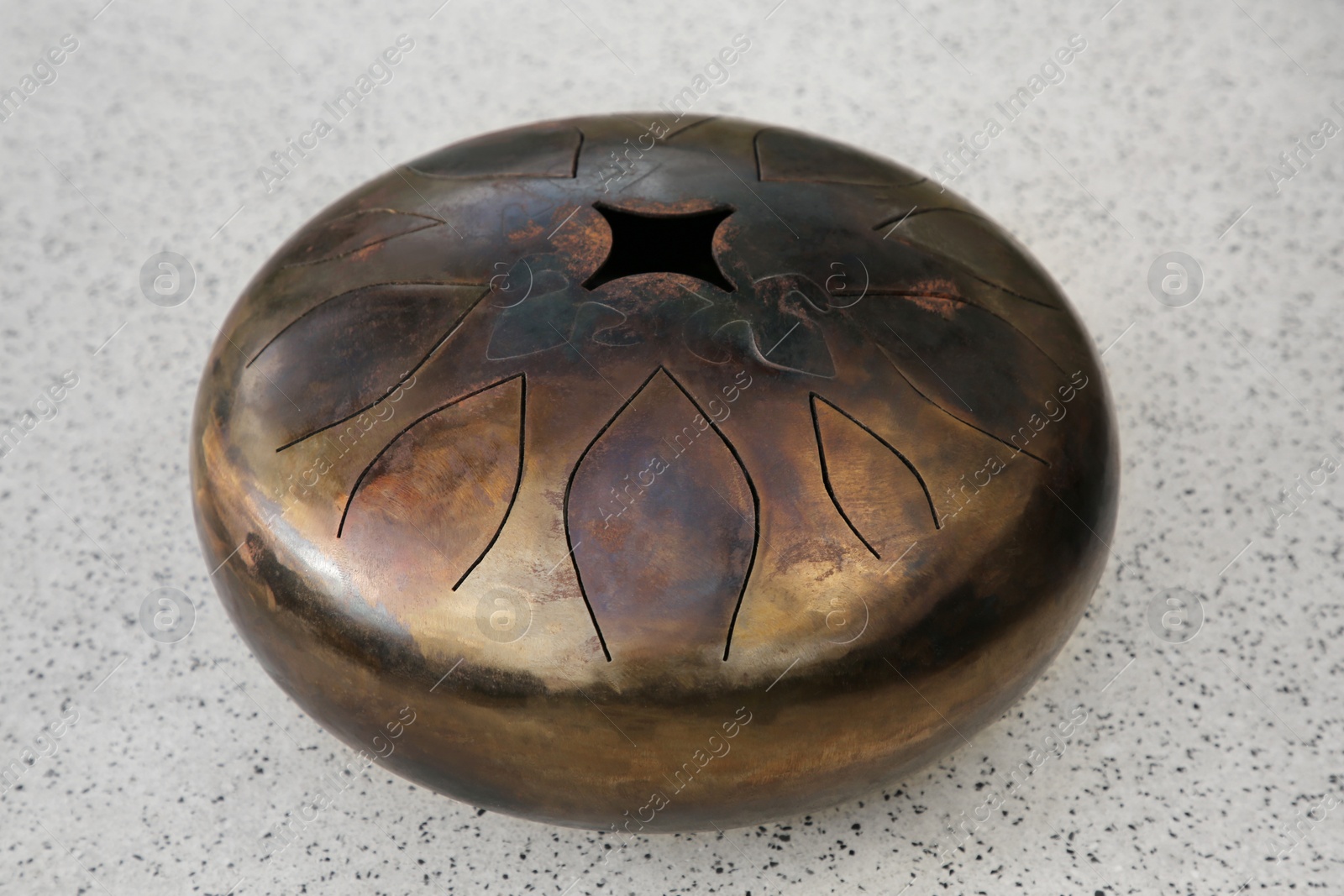 Photo of Steel tongue drum on grey table. Percussion musical instrument