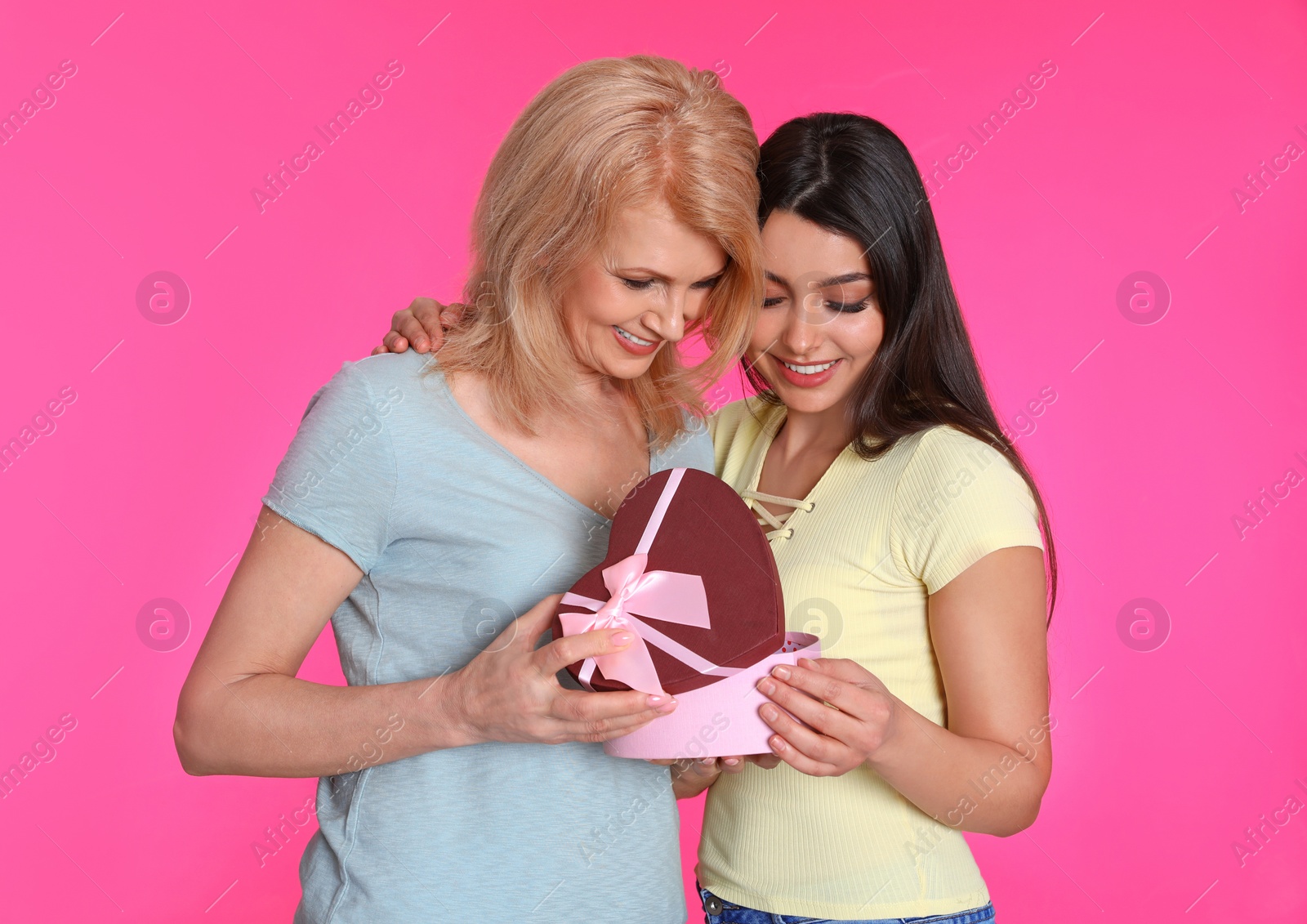 Photo of Young woman congratulating her mature mom on color background. Happy Mother's Day
