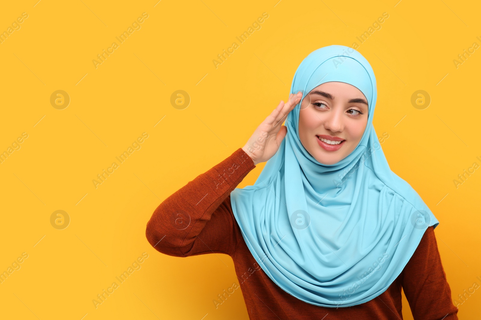 Photo of Portrait of Muslim woman in hijab on orange background