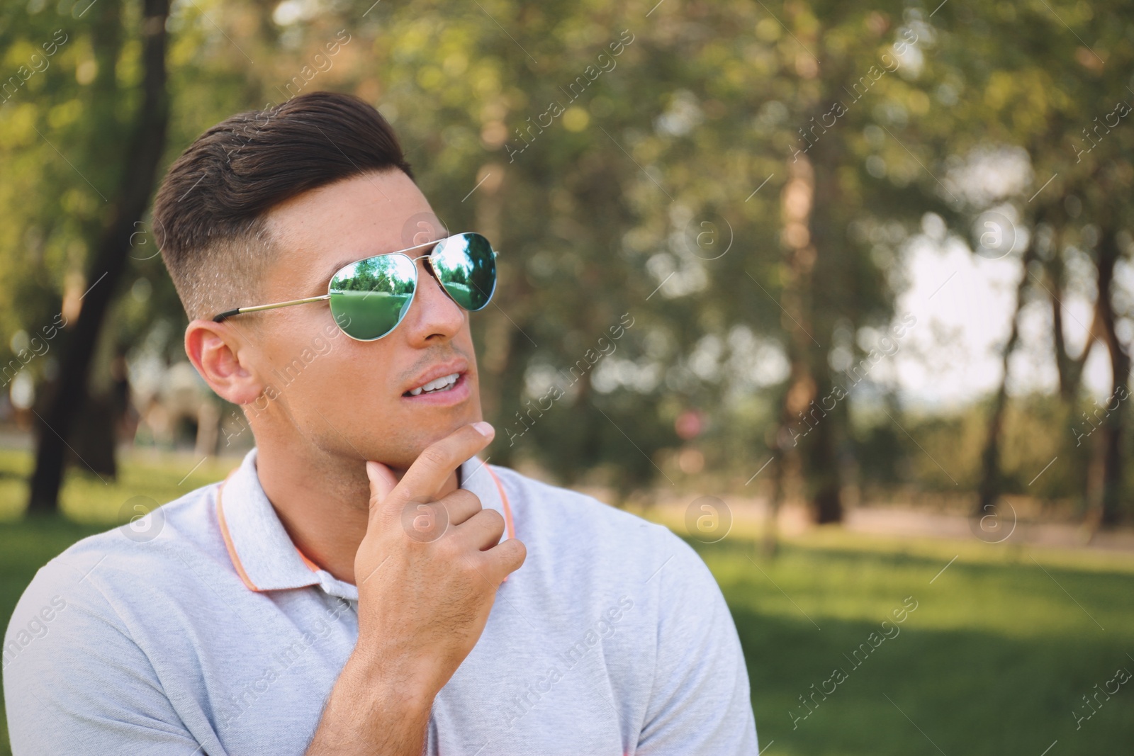 Photo of Handsome man wearing stylish sunglasses in park. Space for text