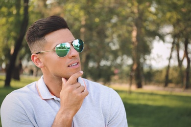 Photo of Handsome man wearing stylish sunglasses in park. Space for text