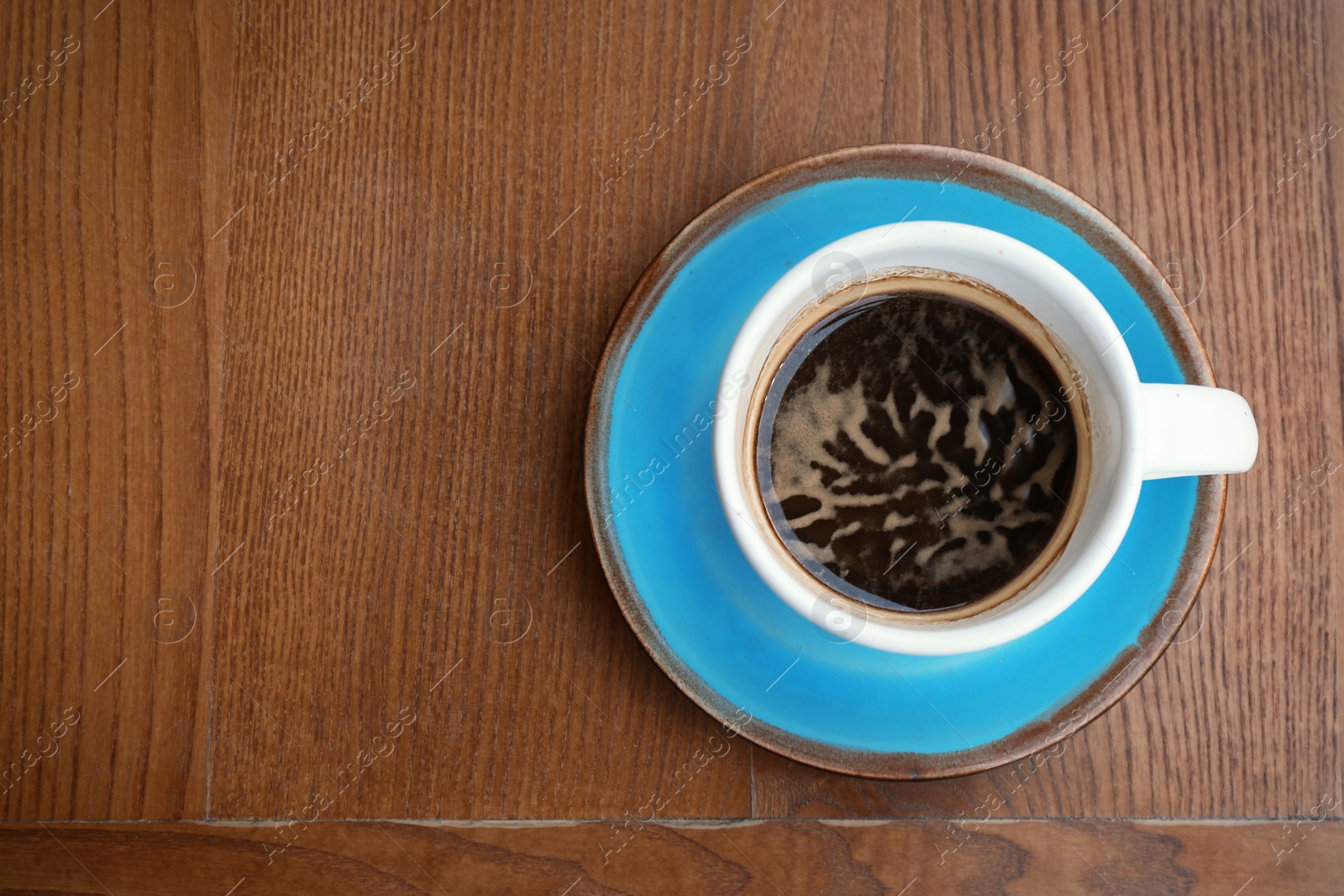 Photo of Cup of fresh aromatic coffee on wooden table, top view