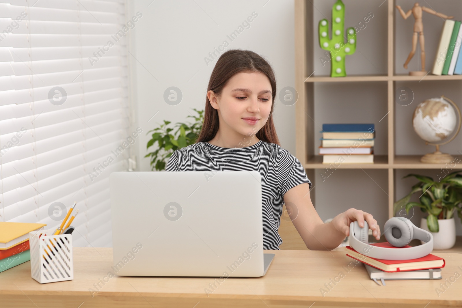 Photo of Cute girl using laptop at desk in room. Home workplace