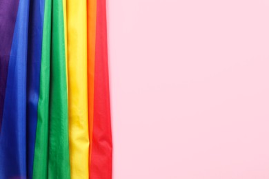 Photo of Rainbow LGBT flag on pink background, top view. Space for text