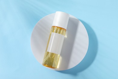 Photo of Bottle of cosmetic oil on light blue background, top view