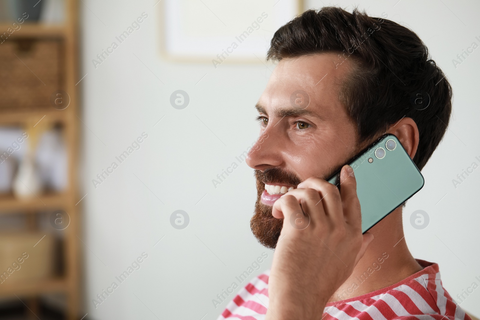 Photo of Handsome man talking on phone at home, space for text