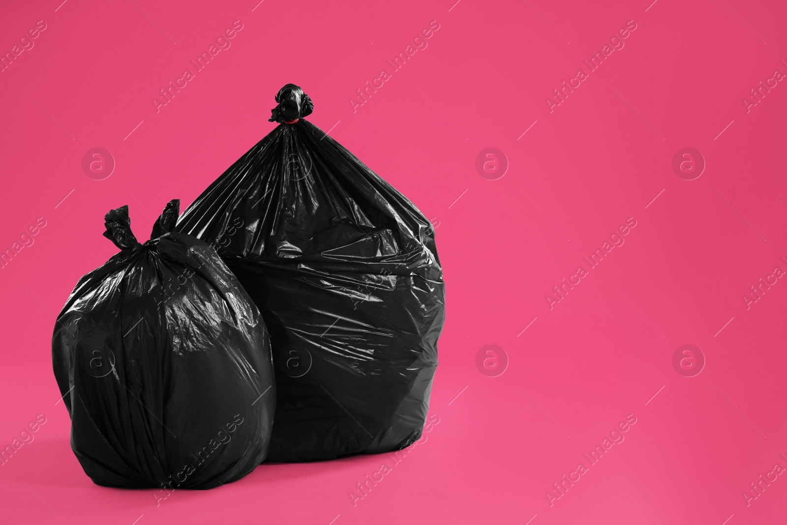 Photo of Trash bags full of garbage on pink background. Space for text