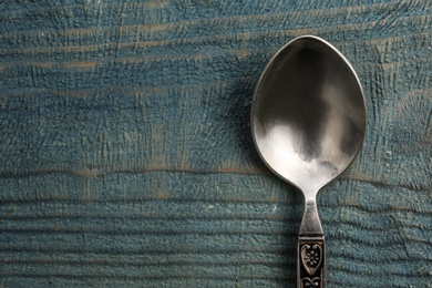 Clean vintage tea spoon and space for text on wooden background, top view