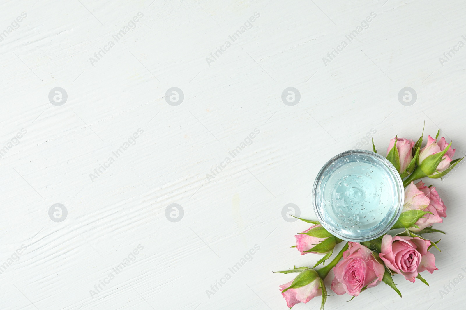 Photo of Flat lay composition with cosmetic gel and beautiful flowers on white wooden table. Space for text