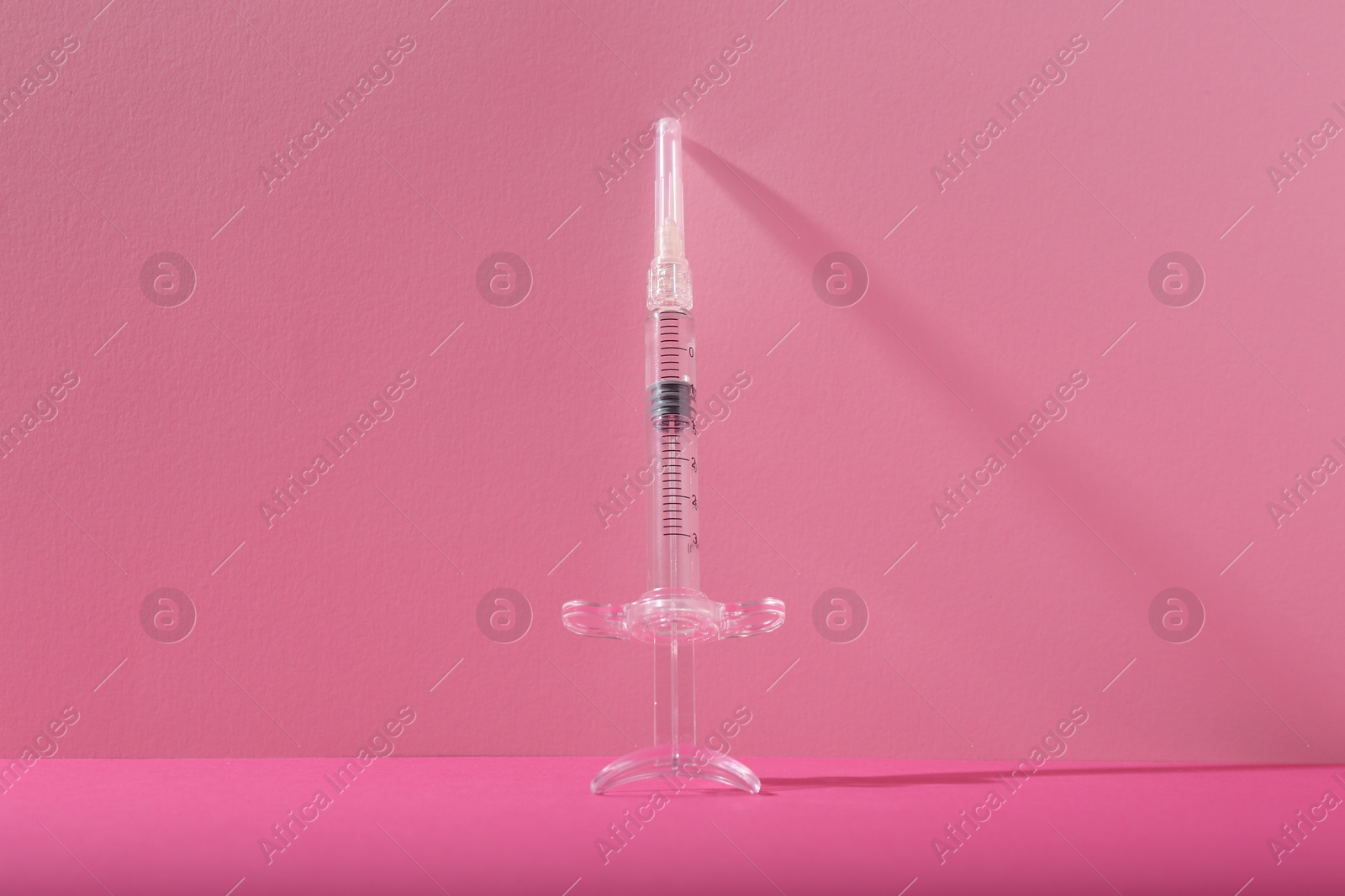 Photo of Cosmetology. One medical syringe on pink background