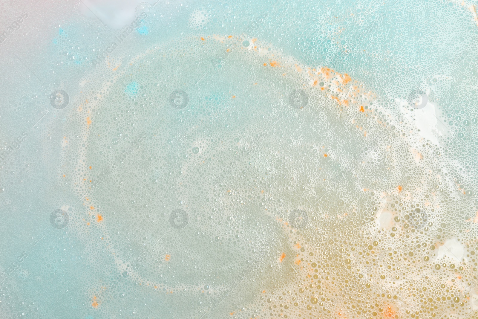 Photo of Colorful foam after dissolving bath bomb in water, closeup