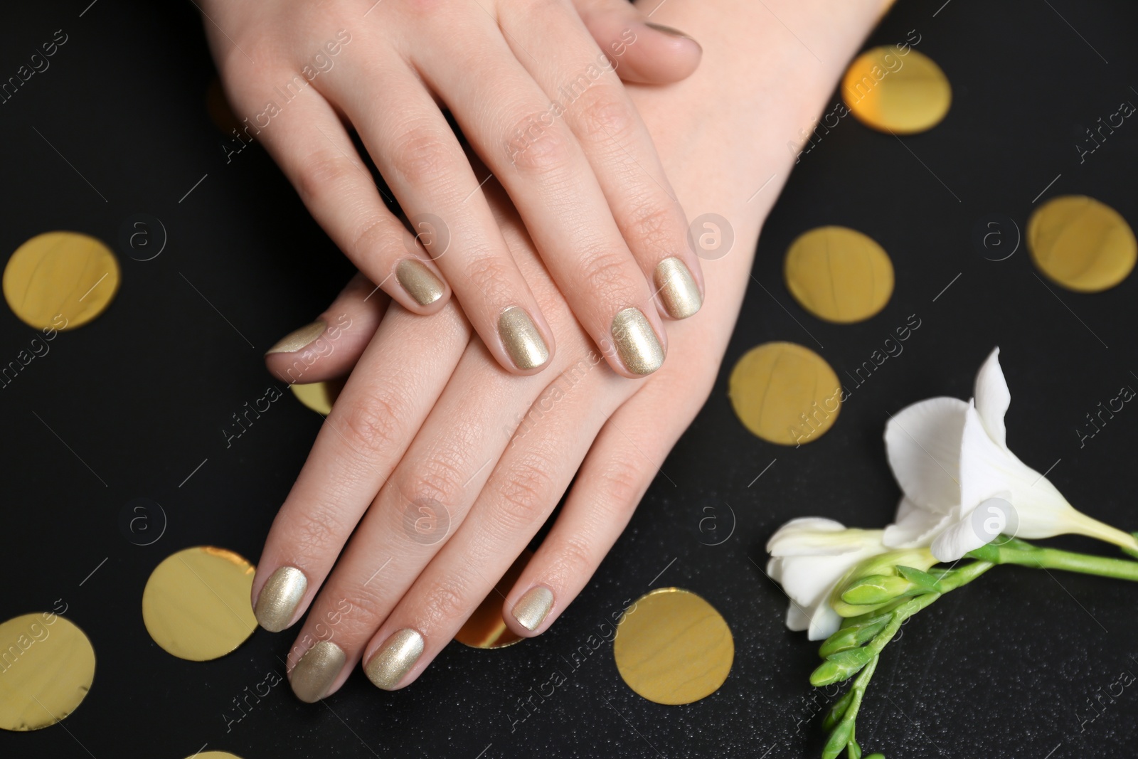 Photo of Woman with golden manicure on black background, closeup. Nail polish trends