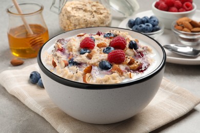 Photo of Tasty oatmeal porridge with toppings served on grey table, closeup
