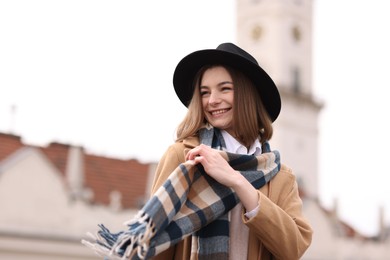 Photo of Beautiful woman in warm scarf and hat outdoors, space for text