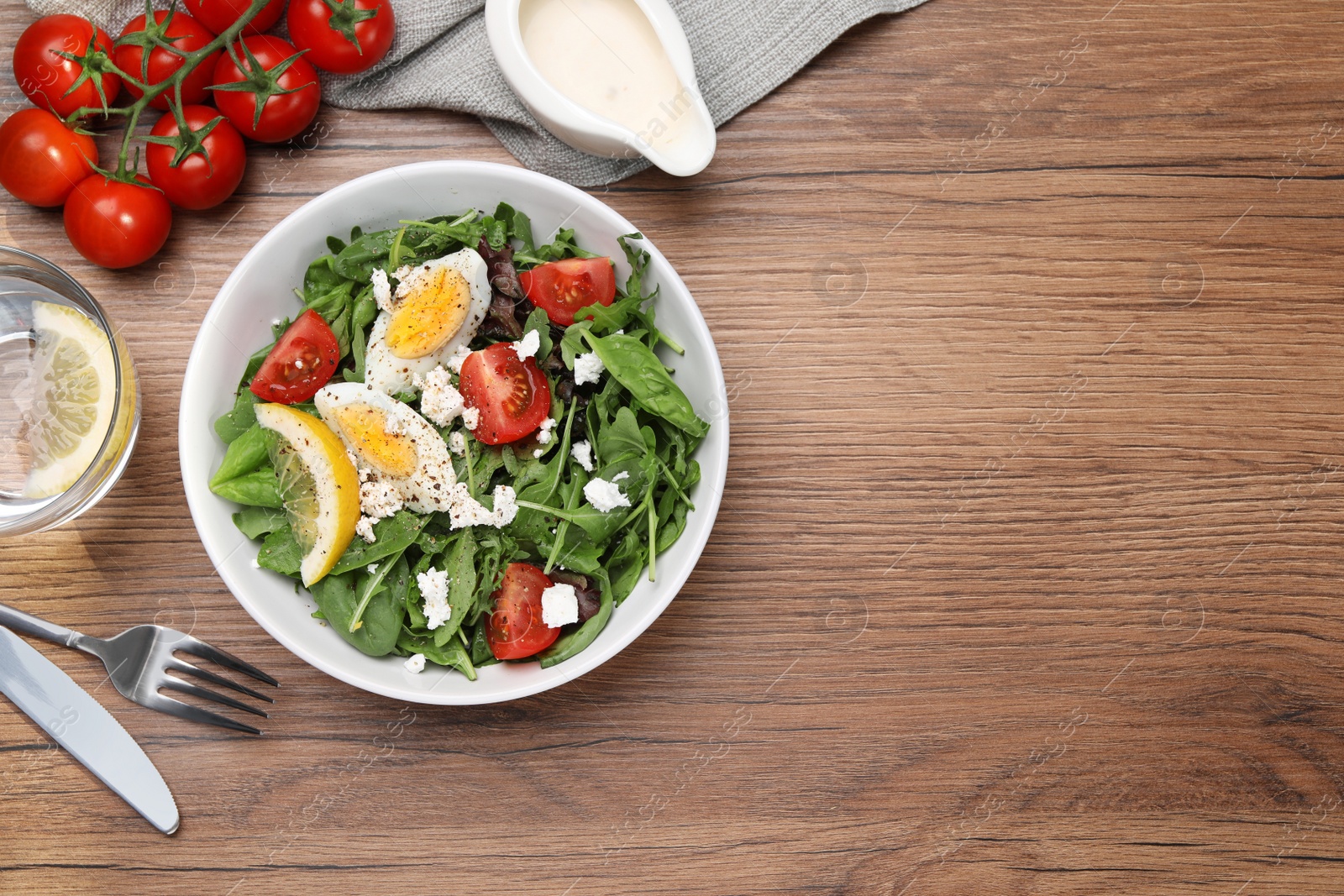 Photo of Delicious salad with boiled egg, tomatoes and cheese served on wooden table, flat lay. Space for text