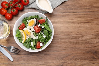 Photo of Delicious salad with boiled egg, tomatoes and cheese served on wooden table, flat lay. Space for text
