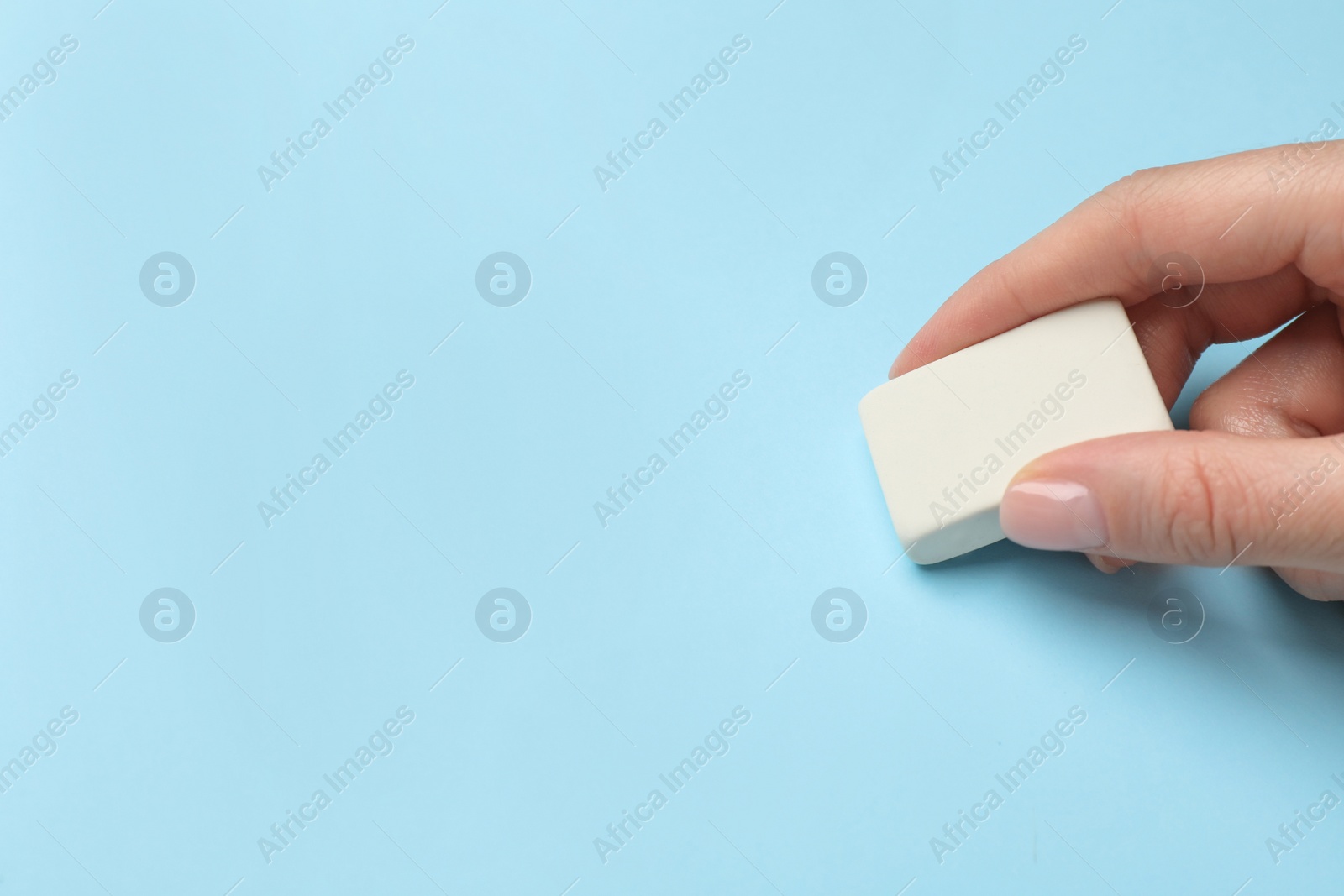 Photo of Woman erasing something on light blue background, closeup. Space for text