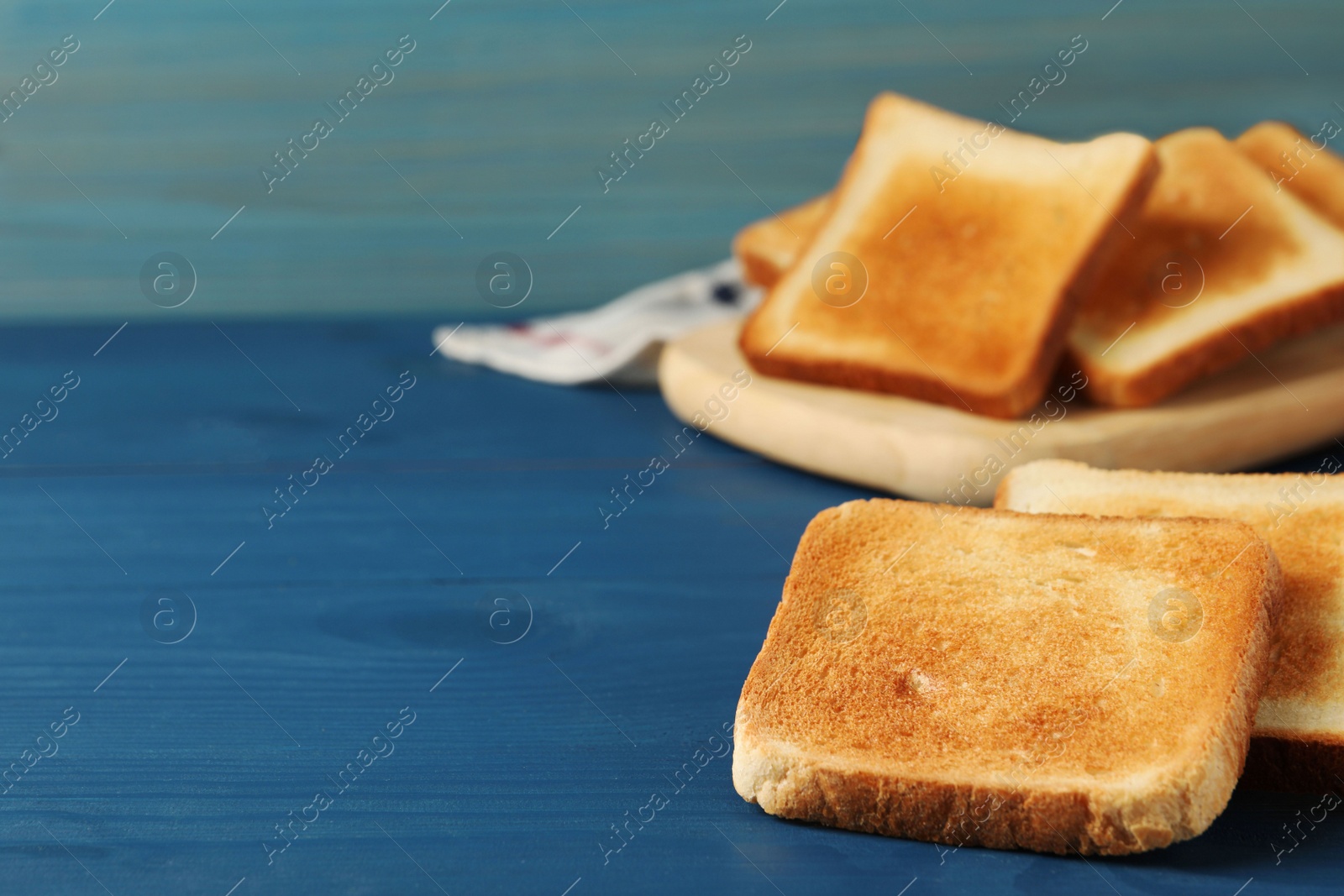 Photo of Slices of tasty toasted bread on blue wooden table. Space for text