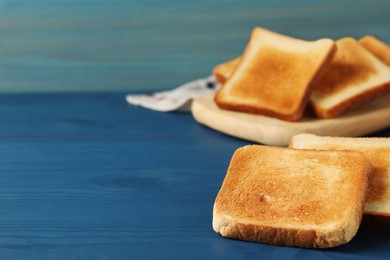 Photo of Slices of tasty toasted bread on blue wooden table. Space for text