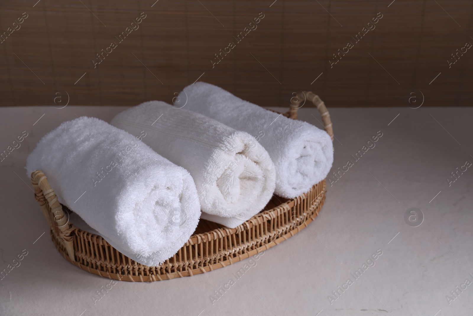 Photo of Rolled terry towels on white table indoors, space for text