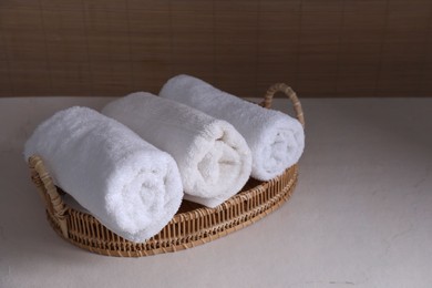 Photo of Rolled terry towels on white table indoors, space for text