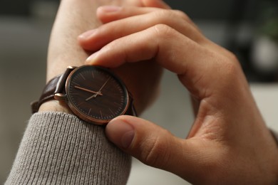 Photo of Man with luxury wrist watch on blurred background, closeup