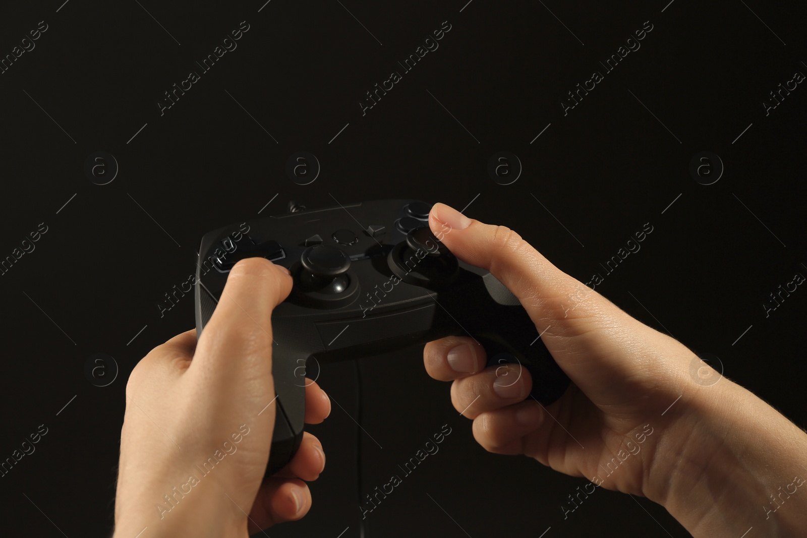 Photo of Woman holding video game controller on black background, closeup