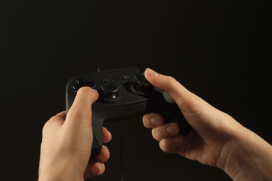 Woman holding video game controller on black background, closeup