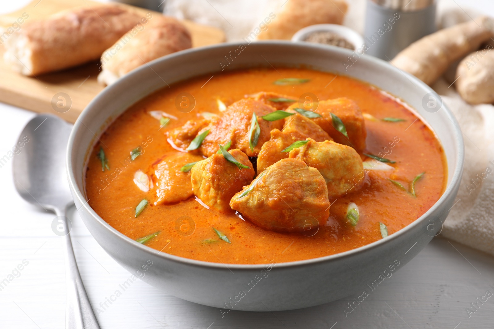 Photo of Bowl of delicious chicken curry on white table