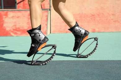 Photo of Woman with kangoo jumping boots in workout park, closeup