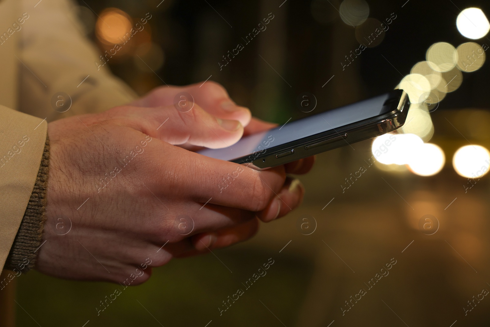 Photo of Man using smartphone on night city street, closeup