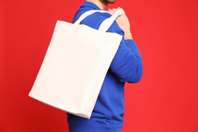 Photo of Young man with eco bag on red background, closeup