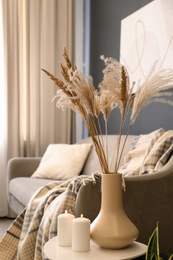 Photo of Dry plants and candles on table in room. Interior design