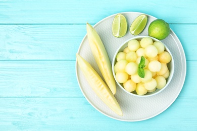 Photo of Melon balls with mint and lime on light blue wooden table, top view. Space for text
