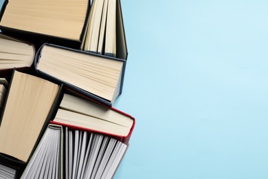 Photo of Many hardcover books on light blue background, top view. Space for text