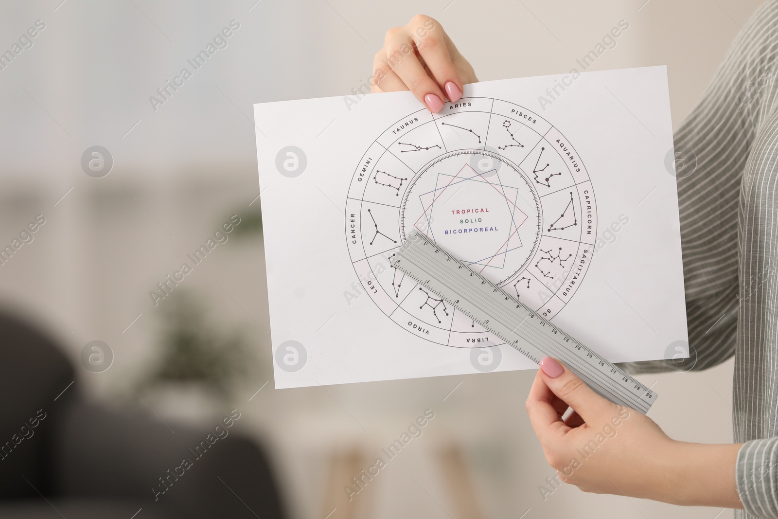 Photo of Astrologer using zodiac wheel for fate forecast indoors, closeup. Fortune telling