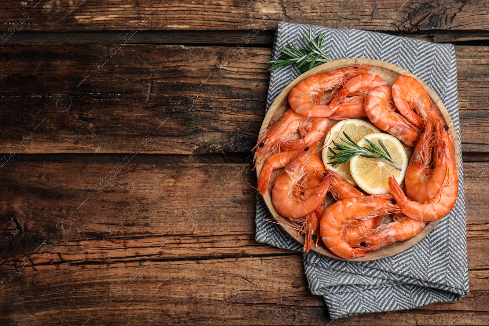 Photo of Delicious cooked shrimps with rosemary and lemon on wooden table, top view. Space for text