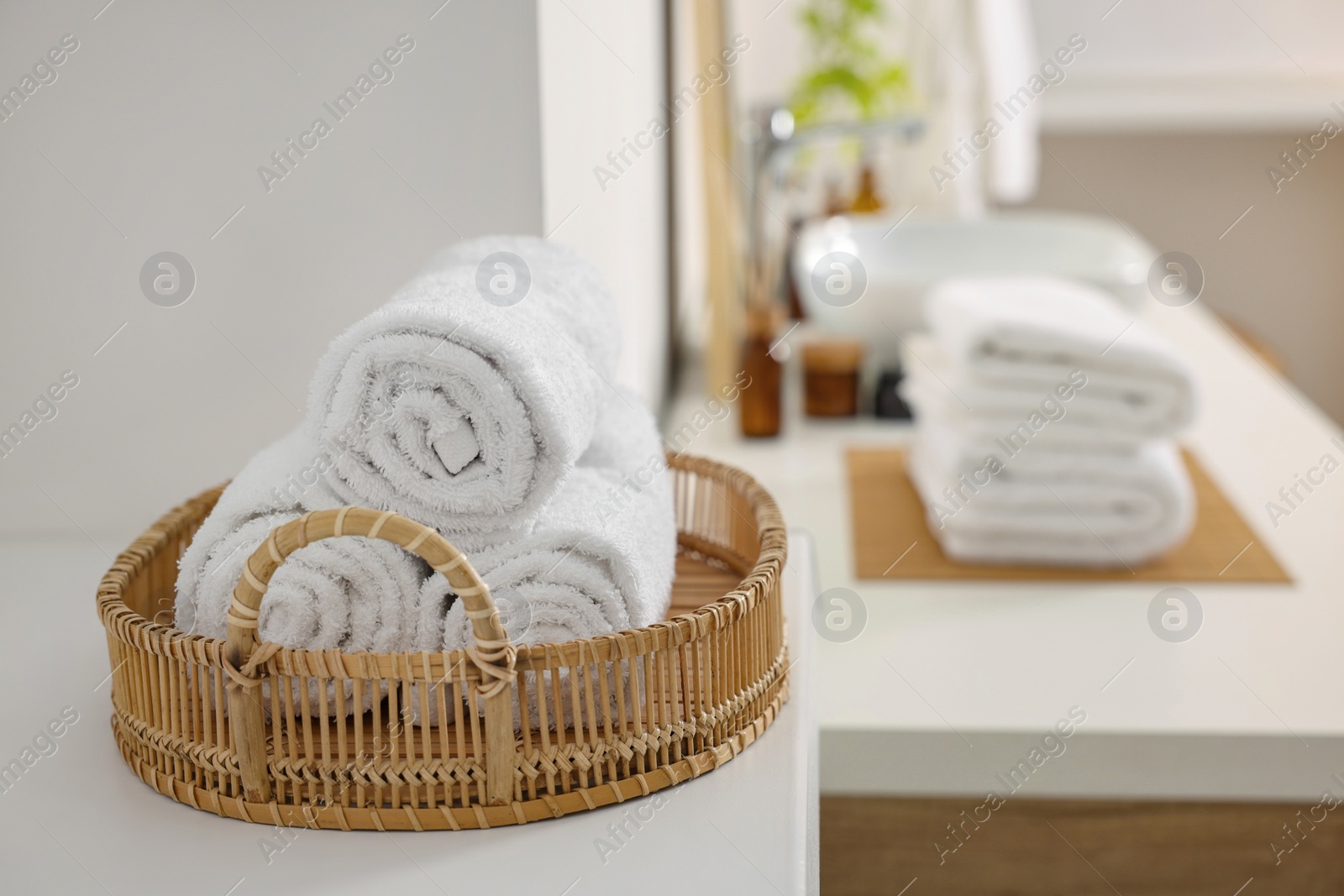 Photo of Rolled soft towels on white table in bathroom. Space for text