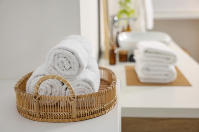 Rolled soft towels on white table in bathroom. Space for text