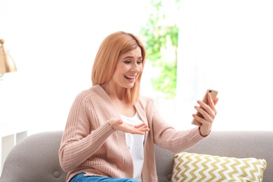 Woman using mobile phone for video chat in living room