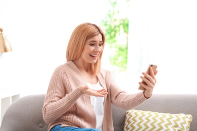 Photo of Woman using mobile phone for video chat in living room