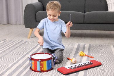 Photo of Little boy playing toy drum at home