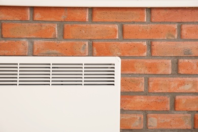 Photo of Heating convector on brick wall, closeup view