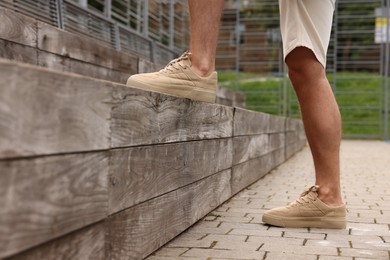 Man wearing pair of stylish sneakers outdoors, closeup