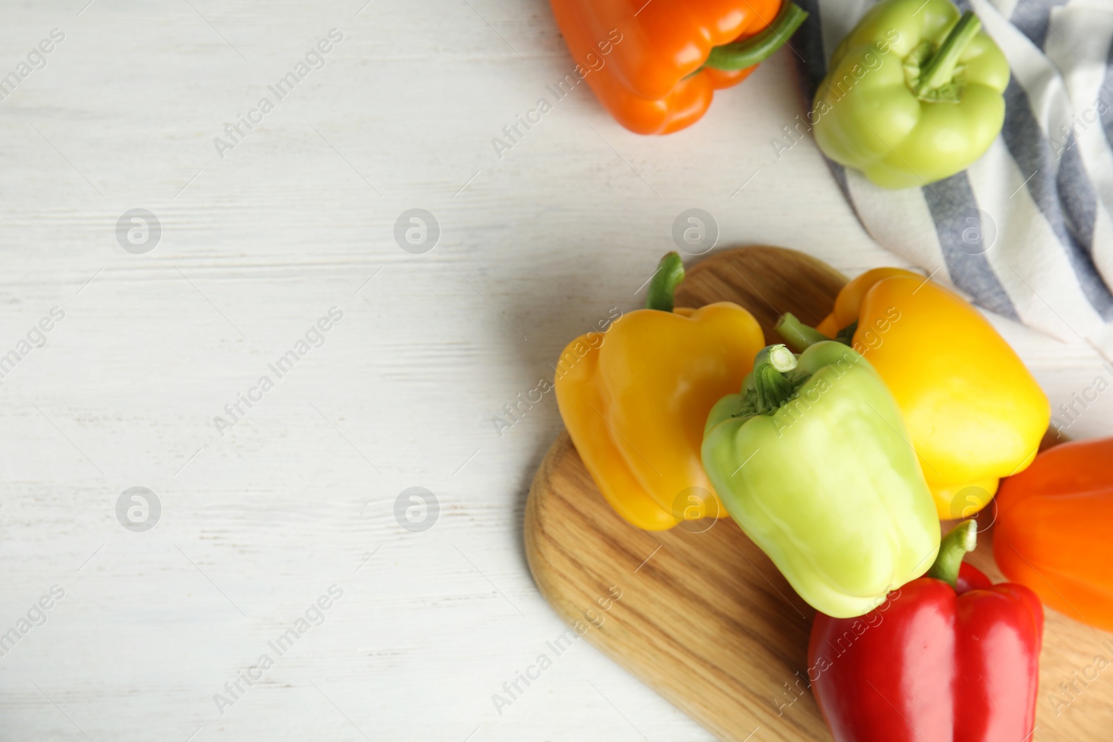 Photo of Fresh ripe bell peppers on white wooden table, top view. Space for text