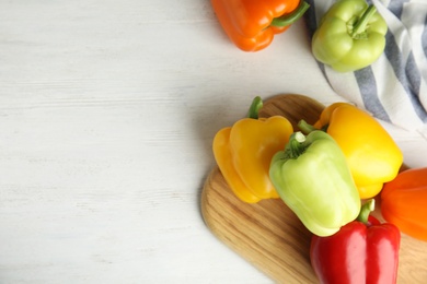 Photo of Fresh ripe bell peppers on white wooden table, top view. Space for text